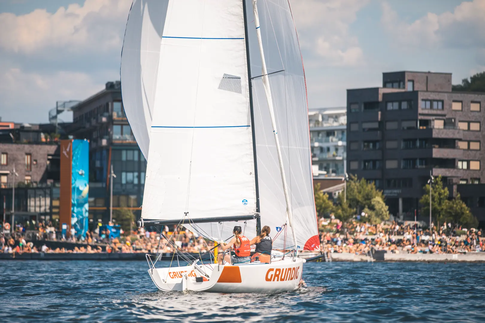 Det er masse mennesker i Bjørvika en varm sommerdag, og dermed fikk treningsregattaen mye oppmerksomhet fra nysgjerrige skuelystne. Foto: Trond Teigen